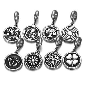 May include: Eight silver charm pendants with different designs, including a tree, a flower, a butterfly, a four-leaf clover, a yin yang symbol, and a tree of life. Each pendant has a silver loop at the top for attaching to a bracelet or necklace.