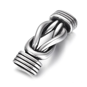 May include: Silver-toned metal toggle clasp with a knotted design. The clasp has a smooth, polished finish and is designed to be used as a closure for necklaces, bracelets, or other jewelry.