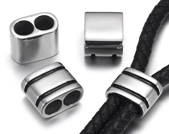 May include: Three silver metal cord end caps, two with double holes and one with a single hole, with black lines around the edges. The cord end caps are shown on a black leather cord.