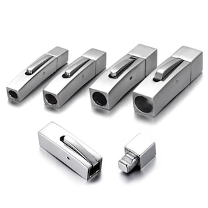 Peut inclure: Cinq fermoirs métalliques argentés pour bracelets ou colliers. Les fermoirs sont rectangulaires et ont un mécanisme coulissant. On voit également un fermoir en gros plan.