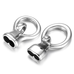 Puede incluir: Dos tapones de extremo de metal plateado para la elaboración de joyas. Cada tapón tiene un bucle redondo y una base en forma de corazón.