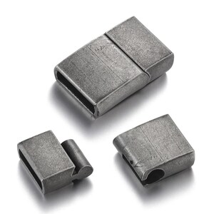 Könnte beinhalten: Drei antike, silberfarbene Magnetverschlüsse. Die Verschlüsse sind rechteckig mit abgerundeten Kanten und mattem Finish. Ein Verschluss ist geschlossen, die anderen beiden sind offen und zeigen die magnetische Verbindung. Ideal für die Schmuckherstellung.