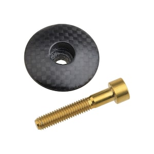 Könnte beinhalten: Eine schwarze Carbon-Lenker-Deckkappe mit einer goldenen Titan-Schraube.