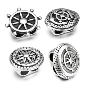 May include: Four silver-toned nautical-themed charms. Designs include a ship's wheel, an anchor with a ship's wheel, a compass rose, and a compass with directional markers. Each charm has a cylindrical shape with a hole for stringing.