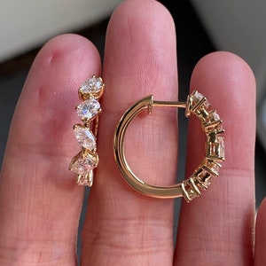 Könnte beinhalten: Ein Paar goldene Creolen mit einer Reihe von klaren, runden und marquiseförmigen Diamanten.