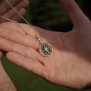Op de afbeelding: Een zilveren ketting met een zilveren kompas hanger. Het kompas heeft een gedetailleerd ontwerp met een ster in het midden.
