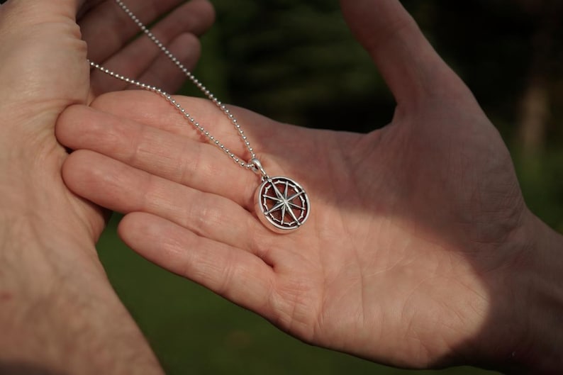 Op de afbeelding: Een zilveren ketting met een zilveren kompas hanger. Het kompas heeft een gedetailleerd ontwerp met een ster in het midden.