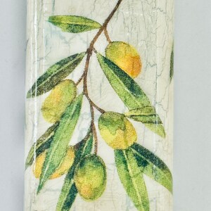 Puede incluir: Una botella de cer&aacute;mica blanca con un acabado desgastado presenta un dise&ntilde;o impreso de ramas de olivo verdes con aceitunas amarillas.
