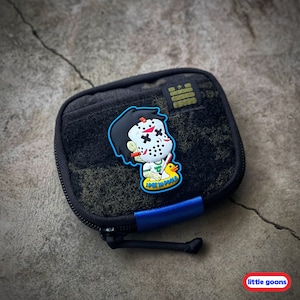 May include: A black zippered pouch with a blue zipper pull and a green, black, and white patch featuring a cartoon character wearing a hockey mask and a yellow rubber ducky. The patch says "ICE MOOLS".