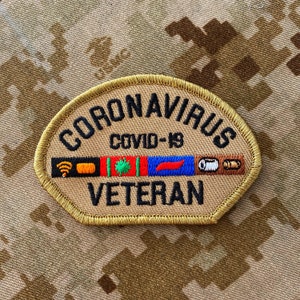 May include: A tan embroidered patch with a gold border featuring the black text CORONAVIRUS COVID-19 and VETERAN. Between the text is a horizontal strip containing icons including a yellow wifi symbol, a green virus, and other small graphics.