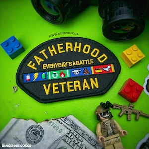 May include: Black patch with yellow text that reads "Fatherhood Everyday's a Battle Veteran". The patch has a row of colorful icons depicting common challenges of fatherhood, including a lightning bolt, a battery, a money bag, a fire, a diaper, a pile of poop, a toolbox, and a sock.