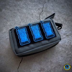 May include: Three blue and black tiki-style patches with the text "Tiki Souls" on a gray pouch.