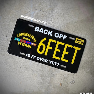 May include: Black and yellow license plate with the text "BACK OFF 6 FEET - IS IT OVER YET?" and "CORONAVIRUS COVID-19 VETERAN" in a ribbon. The year 2020 is printed in the top right corner.