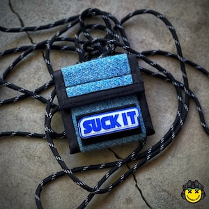 May include: A small blue and black wallet with a black strap. The wallet has a blue patch with the text "SUCK IT" in white letters with a blue outline.