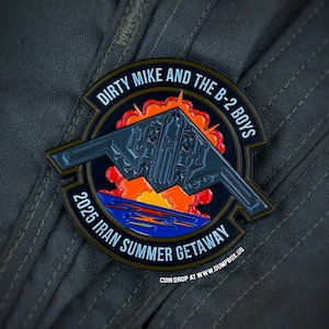 May include: A circular, dark metal coin with the text "DIRTY MIKE AND THE B-2 BOYS" and "2025 IRAN SUMMER GETAWAY." The coin features a B-2 bomber design over a sunset scene. The website address "DUMPBOX.US" is also visible.