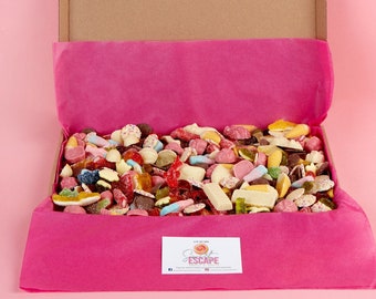 Puede incluir: Una caja de cartón rosa y marrón llena de una variedad de caramelos coloridos. La caja está abierta y los caramelos se están derramando. La caja tiene un forro de papel de seda rosa y una pegatina que dice "Sweet Escape".