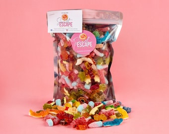 Puede incluir: Una bolsa de plástico transparente llena de una variedad de caramelos gomosos de colores. La bolsa está etiquetada con "Sweet Escape" y tiene un logotipo rosa y blanco. Los caramelos se derraman de la bolsa sobre una superficie rosa.