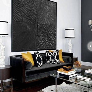 Puede incluir: Un sof&aacute; de terciopelo negro con cojines decorativos de patrones amarillos, negros y blancos se encuentra en una sala de estar moderna con una alfombra de patrones negros y blancos, una mesa de caf&eacute; de vidrio y una gran obra de arte abstracta en blanco y negro en la pared.