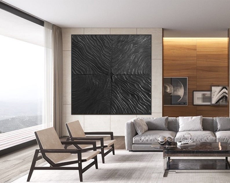 Puede incluir: Una pieza de arte de pared abstracta en blanco y negro con una superficie texturizada. El arte est&aacute; colgado en una pared en una sala de estar moderna con un sof&aacute; gris, dos sillas y una mesa de caf&eacute;.