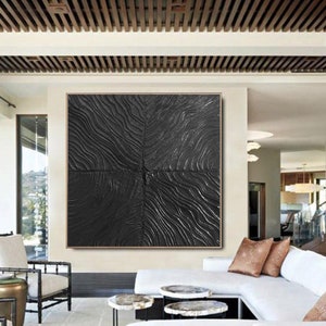 Puede incluir: Una gran pintura abstracta en blanco y negro con una superficie texturizada. La pintura est&aacute; colgada en una pared de una sala de estar moderna.