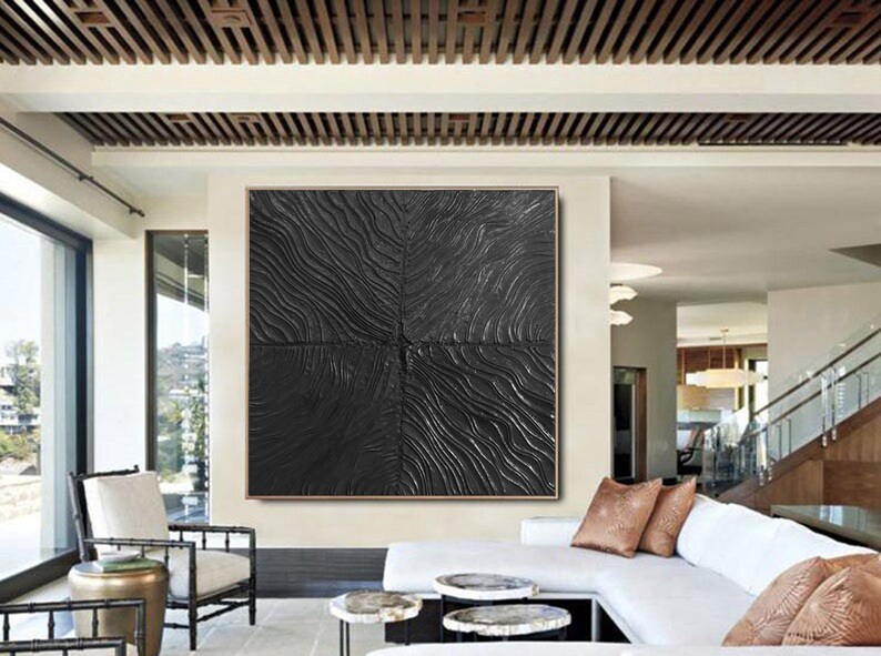 Puede incluir: Una gran pintura abstracta en blanco y negro con una superficie texturizada. La pintura est&aacute; colgada en una pared de una sala de estar moderna.