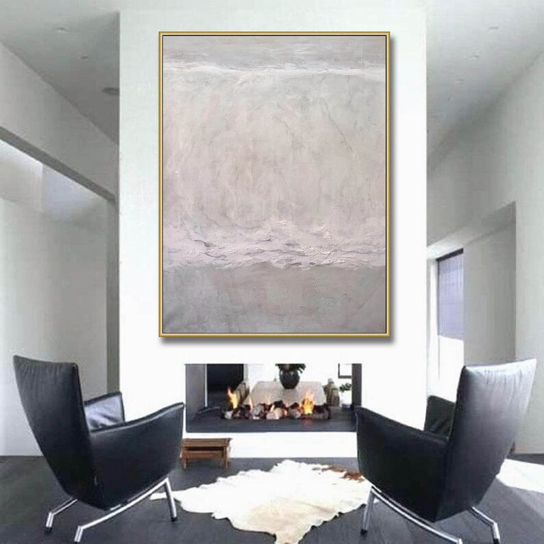 May include: Abstract painting in shades of gray and white with a textured surface. The painting is framed in a gold frame and is hanging on a white wall above a fireplace.
