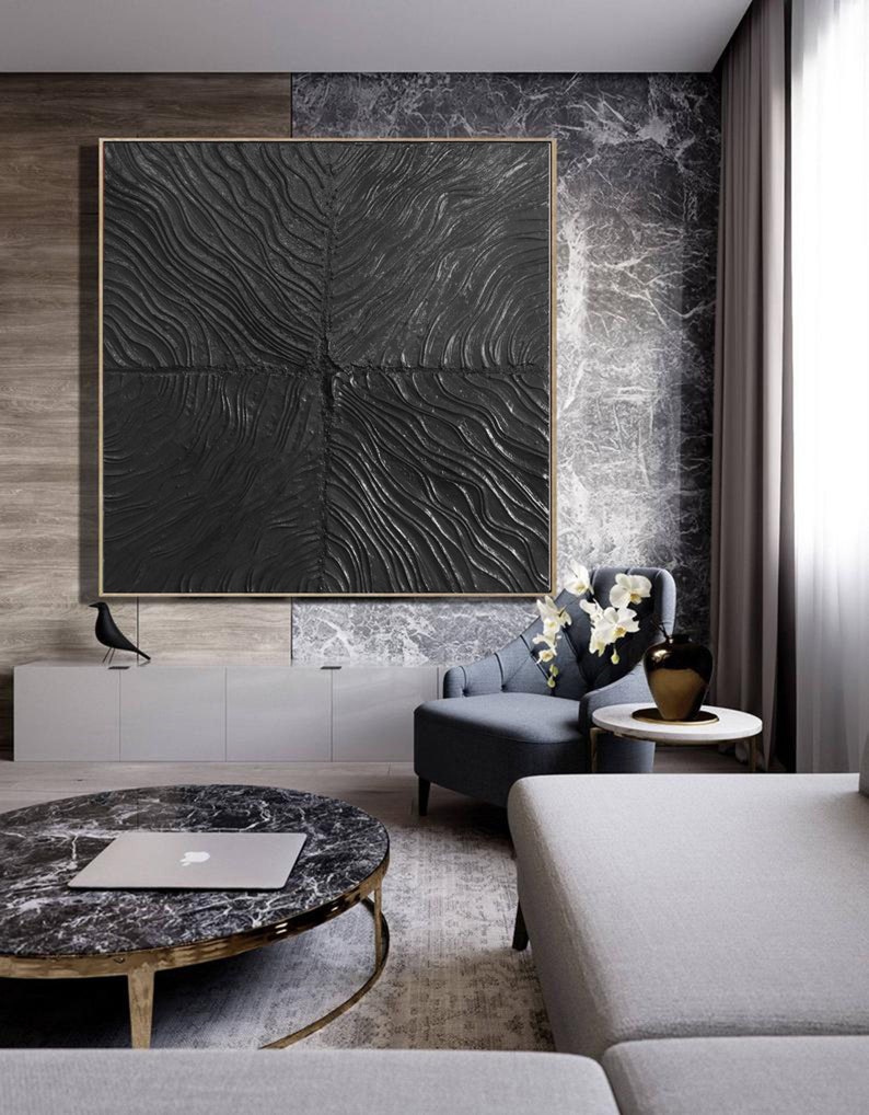 Puede incluir: Una pintura abstracta en blanco y negro con una superficie texturizada. La pintura est&aacute; enmarcada en un fino marco dorado y est&aacute; colgada en una pared de una sala de estar.