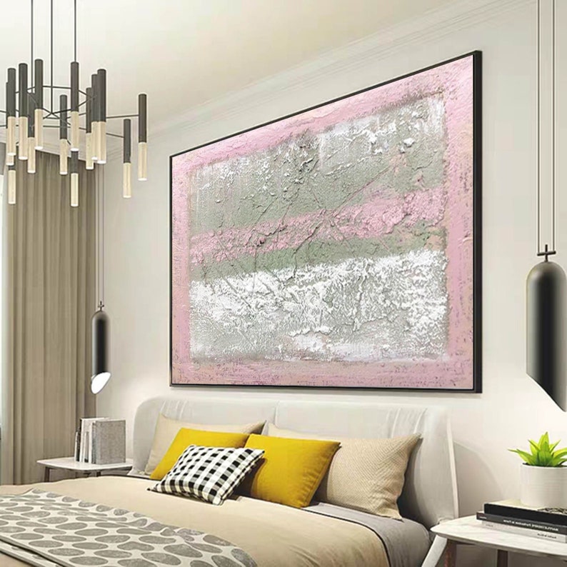 May include: Abstract painting with pink and silver stripes on a white background. The painting is framed in black and hangs on a wall in a bedroom.