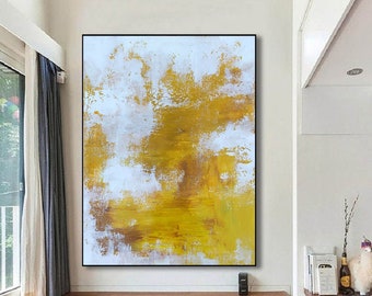 May include: Large abstract painting with a black frame. The artwork features a textured design with white, yellow, and brown brushstrokes. The painting is displayed on a white wall above a wooden floor.