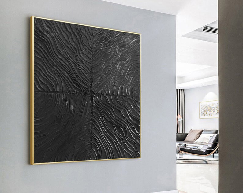 Puede incluir: Una pieza de arte de pared abstracto en negro y dorado con un patr&oacute;n texturizado y ondulado. El arte est&aacute; enmarcado en un fino marco dorado.