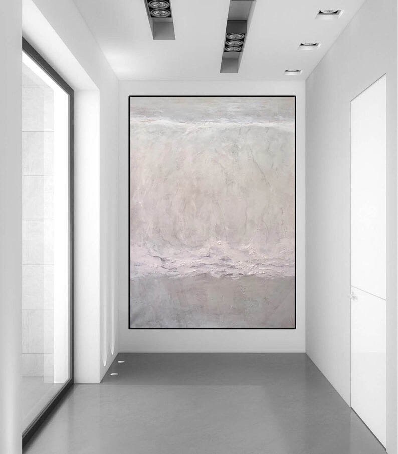May include: A large abstract painting in shades of white, gray, and light pink hangs on a white wall in a modern hallway. The painting has a textured surface and appears to depict a landscape or seascape.