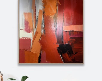 Puede incluir: Pintura abstracta con trazos audaces de pintura roja, naranja y blanca. La pintura está enmarcada en un marco de madera natural.