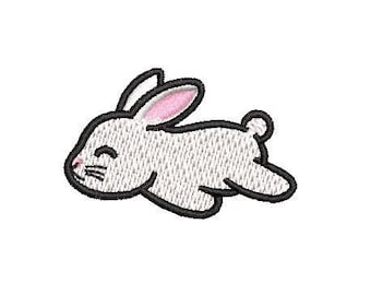 May include: A white rabbit with pink ears is lying on its side with its eyes closed. The rabbit is outlined in black.