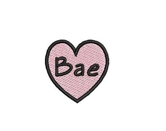 May include: Pink heart-shaped patch with a black outline and the word "Bae" written in black inside.