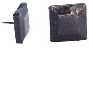 May include: Two dark brown, square-headed nails. One nail is shown from the side, revealing the nail's point. The other nail is shown from the front, displaying the square head's textured surface. These nails are likely for furniture or decorative use.