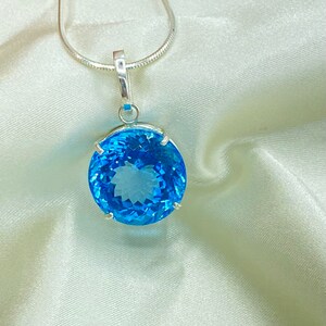 May include: A silver chain necklace with a round blue topaz pendant.