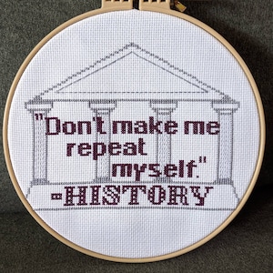 May include: White embroidery hoop with a gray and white illustration of a building with columns and the text "Don't make me repeat myself." "HISTORY" in maroon thread.