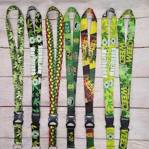 May include: Seven lanyards with cannabis leaf and related designs. The lanyards display the words "Marihuana" and "Weed", and the number "420". The colour scheme includes green, yellow, and black. Each lanyard has a black plastic clasp.