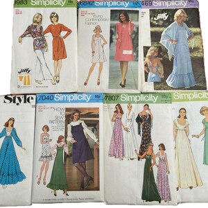 May include: A collection of eight vintage Simplicity and Style sewing pattern envelopes featuring illustrations of various dresses, including maxi, midi, and jumper styles. Each paper envelope displays garment sketches, model photos, and pattern numbers.