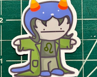 May include: A cartoon sticker of a character wearing a blue hat with orange horns, a green jacket, and a grey shirt with a Leo zodiac symbol. The character has a neutral expression.