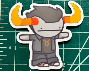 May include: A cartoon sticker of a gray and black character with orange horns and a Taurus symbol on a black shirt. The character has a white face with red eyes and a black outline.