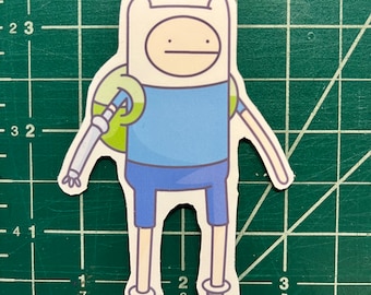May include: A cartoon sticker of Finn the Human from the animated series Adventure Time. Finn is wearing a blue shirt, blue shorts, and brown boots. He has a green backpack and a white dog-like head with a brown nose and eyes.