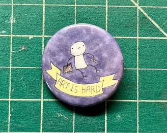 May include: A purple button with a white stick figure holding a paintbrush and a yellow banner that says "Art is Hard".