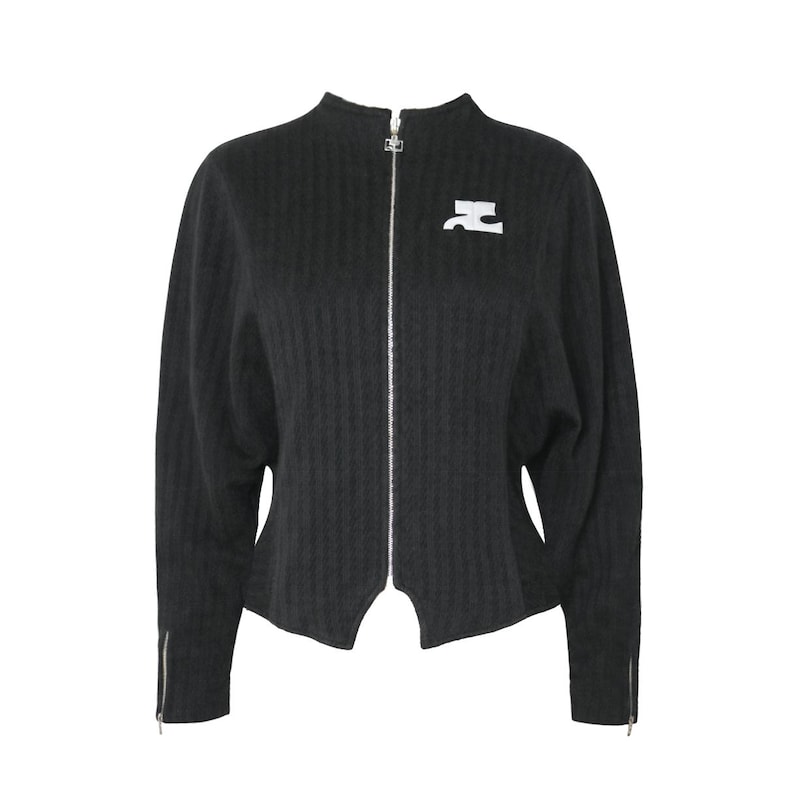 May include: A black zip-up jacket with a high collar and a white logo on the chest. The jacket has a textured, ribbed pattern and silver zippers on the front and sleeves. The sleeves are long and the jacket has a unique cut at the bottom.