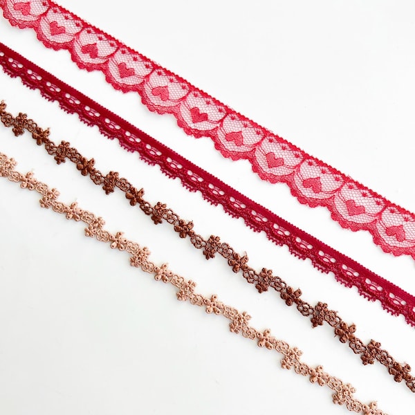 Cinta de encaje elástico con borde festoneado, calado, bordado floral en forma de corazón y ribete de puntilla marrón rojizo.