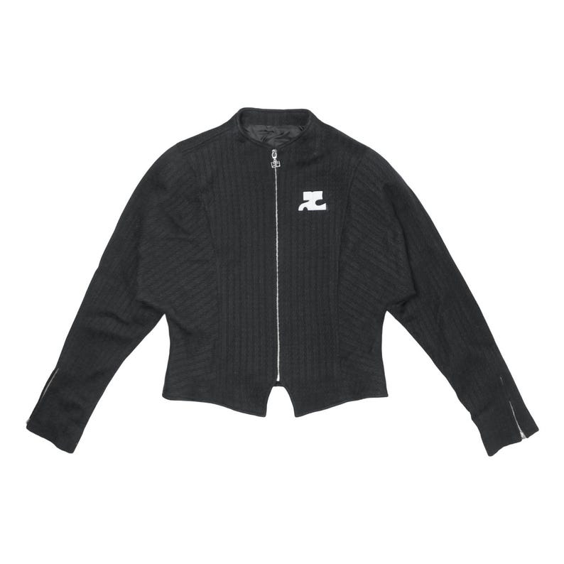 May include: Black zip-up jacket with a ribbed texture and a small white logo on the chest. The jacket has long sleeves with zippers at the cuffs. The collar is a stand-up style.