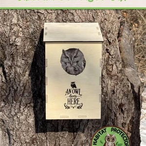 May include: A wooden owl nest box with a cutout of an owl and the text "An owl lives here". The box is mounted on a tree trunk. A round green patch with the text "Habitat Protector" and an owl sitting on a turtle is attached to the tree trunk.