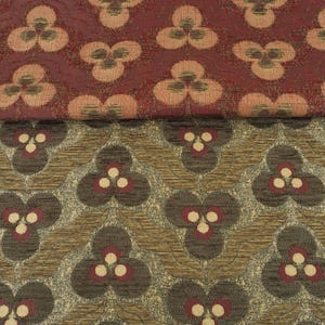 May include: Close-up of two patterned fabrics. The top fabric is a deep red with a repeating floral design in shades of peach and brown. The bottom fabric is a mix of brown, gray, and gold with a similar floral pattern in brown and red.