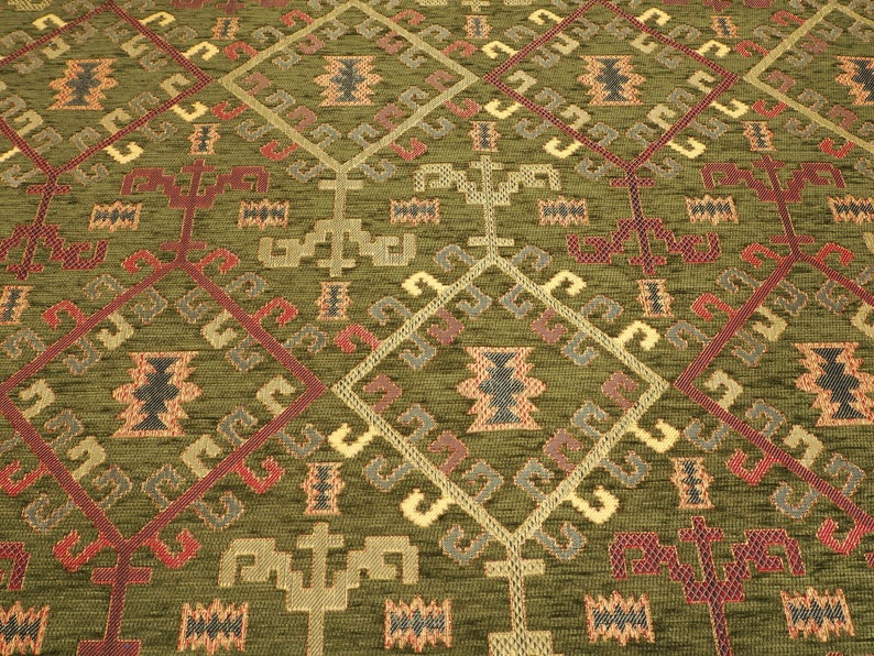 May include: Green fabric with a repeating geometric pattern in shades of red, brown, gold, and gray. The pattern features stylized trees and diamond shapes.