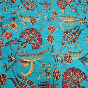 Könnte beinhalten: Nahaufnahme eines türkisfarbenen Stoffes mit detailliertem Blumenmuster. Das Design zeigt rote, braune und gelbe stilisierte Blumen und Blätter. Der Stoff hat ein strukturiertes Aussehen, das auf ein gewebtes Material hindeutet, das sich für Polster oder Dekorationszwecke eignet.